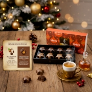 Luxury Greek Pralines flavor breakdown: Gianduja (sweet, creamy, hazelnut milk chocolate) vs. Dark Chocolate Salted Caramel (intense, rich cocoa). Paired with Greek coffee and Mastiha liqueur.