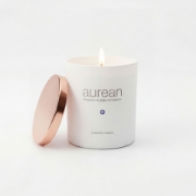 Lit Aurean Golden Lumos luxury candle in a white matte vessel with a rose gold lid, handcrafted for elenianna.