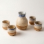 Handmade ceramic carafe and 4 shot glasses set with dual-tone blue and sandy glaze on white background.